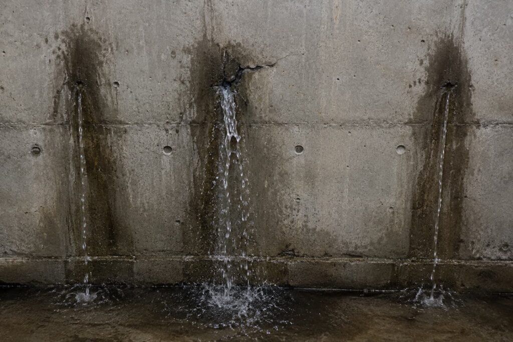 Problema de filtraciones activas en sótano de hormigón antes de aplicar un sistema de impermeabilización.